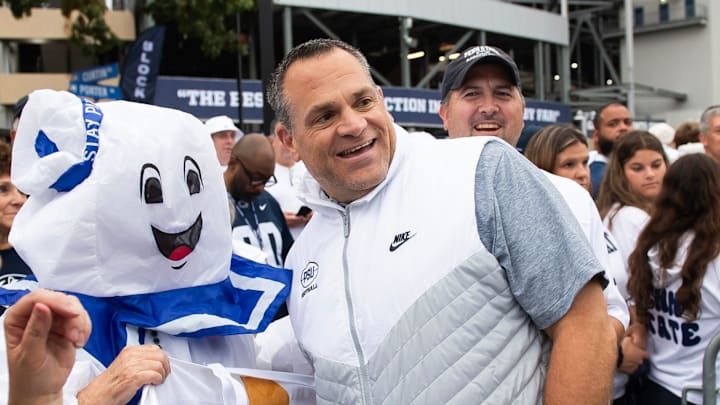 Penn State athletic director Pat Kraft, right, poses for a photo with a group of costumed fans outside Beaver Stadium before a Big Ten football game against Illinois, Saturday, Sept. 28, 2024, in State College, Pa.