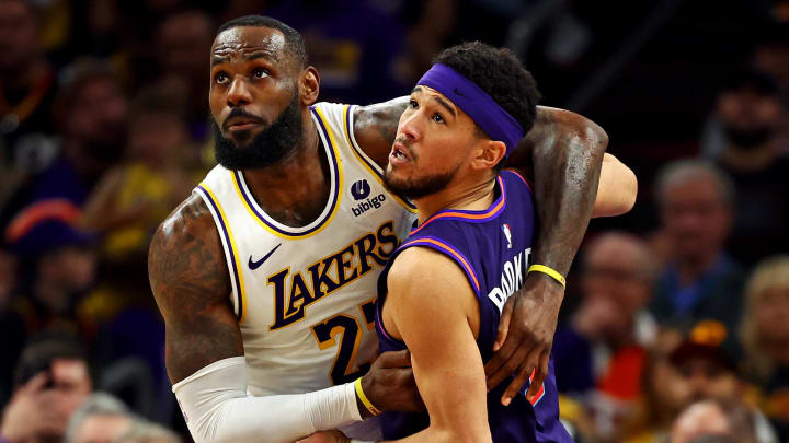 Feb 25, 2024; Phoenix, Arizona, USA; Los Angeles Lakers forward LeBron James (23) and Phoenix Suns guard Devin Booker (1) go for the ball during the second quarter at Footprint Center. Mandatory Credit: Mark J. Rebilas-USA TODAY Sports