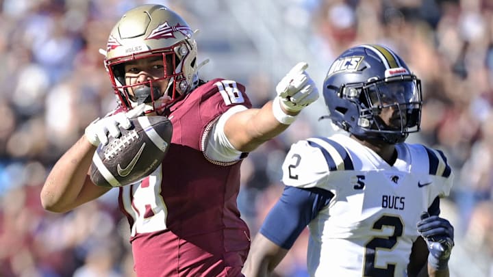 Nov 23, 2024; Tallahassee, Florida, USA; Florida State Seminoles tight end Landen Thomas (18) celebrates a first down grab as Charleston Southern Buccaneers safety Davion Williams (2) looks on during the second half of the game at Doak S. Campbell Stadium. Mandatory Credit: Melina Myers-Imagn Images