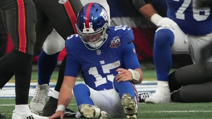 New York Giants quarterback Tommy DeVito holds his knee after taking a hard hit.
