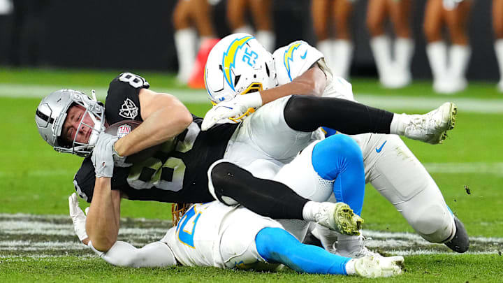 Jan 5, 2025; Paradise, Nevada, USA; Las Vegas Raiders tight end Brock Bowers (89) is tackled by Los Angeles Chargers safety Tony Jefferson (23) and Los Angeles Chargers linebacker Junior Colson (25) during the fourth quarter at Allegiant Stadium. Mandatory Credit: Stephen R. Sylvanie-Imagn Images