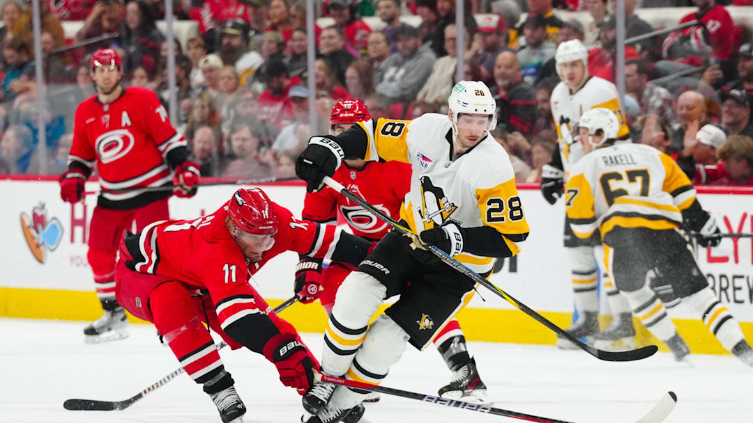 Nov 7, 2024; Raleigh, North Carolina, USA;  Pittsburgh Penguins defenseman Marcus Pettersson (28) skates with the puck against Carolina Hurricanes center Jordan Staal (11) during the third period at Lenovo Center. Mandatory Credit: James Guillory-Imagn Images