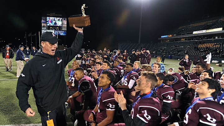 Aquinas head coach Chris Battaglia brings the Section V Class AA championship trophy to his players after the 2015 final at Sahlen's Stadium. Battaglia won nine Section V titles and four state titles at Aquinas from 2006-2016.