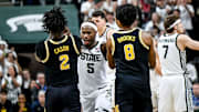 Michigan State's Tre Holloman, center, pushes Michigan's L.J. Cason, left, and Phat Phat Brooks, right, back off the Spartans logo as senior teammates prepare to kiss the floor during the second half on Sunday, March 9, 2025, at the Breslin Center in East Lansing.