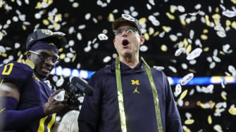 Michigan head coach Jim Harbaugh celebrates during the trophy presentation after the 34-13 win over