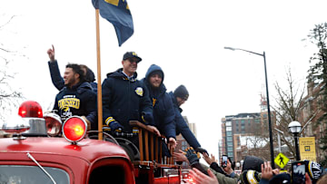 Michigan fans rush an old fire truck to shake hands with Michigan head football coach Jim Harbaugh