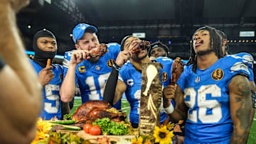 Detroit Lions quarterback Jared Goff (16), defensive tackle DJ Reader (98), wide receiver Amon-Ra St. Brown (14), running back Jahmyr Gibbs (26), linebacker Al-Quadin Muhammad (69) celebrate their win against the Chicago Bears with a turkey drumstick after winning 23-20 on Thanksgiving Day at Ford Field in Detroit on Thursday, Nov. 28, 2024.