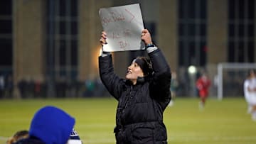 Notre Dame women's soccer junior Sophia Fisher holds a sign directed toward Indiana fans during an NCAA Tournament men's soccer quarterfinal game between the Irish and Hoosiers Saturday, Dec. 2, 2023, at Alumni Stadium in South Bend.