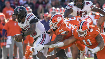 Nov 30, 2024; Clemson, South Carolina, USA; South Carolina quarterback LaNorris Sellers (16) runs by Clemson defensive tackle Payton Page (55) and defensive lineman Peter Woods (11) during the fourth quarter at Memorial Stadium. Mandatory Credit: Ken Ruinard-Imagn Images