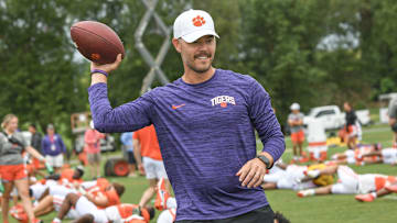 Clemson offensive coordinator Garrett Riley throws a ball as players warm up during preseason practice in Jervey Meadows in Clemson, S.C. Thursday, August 10, 2023.