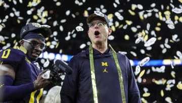 Michigan head coach Jim Harbaugh celebrates during the trophy presentation after the 34-13 win over
