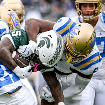 Michigan State's Makhi Frazier, center, is tackled by UCLA after a gain during the first quarter on Saturday, Oct. 11, 2025, at Spartan Stadium in East Lansing.