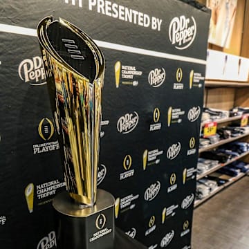 Fans stop to take photos with the College Football National Championship trophy at Meijer in Ypsilanti, Mich. on Thursday, Jan. 11, 2024. The trophy is going on a tour for fans to see presented by Dr. Pepper.