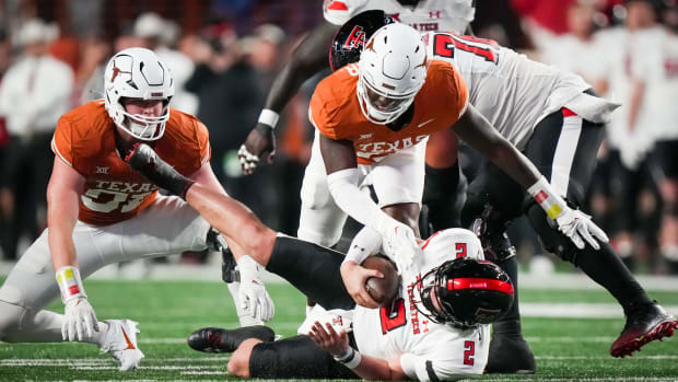 Texas linebacker Anthony Hill Jr. (0) and Texas defensive end Ethan Burke (91) tackle Texas Tech quarterback Behren Morton (2