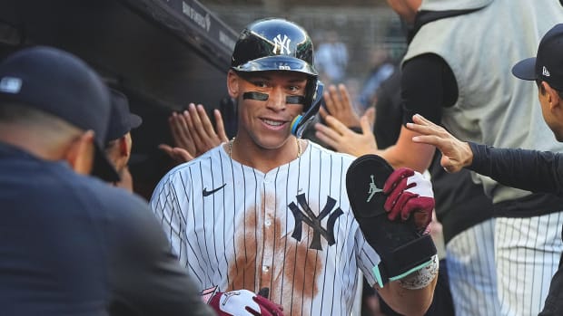Aaron Judge high fives his Yankees teammates in the dugout.