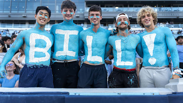 Five UNC fans with “BILL!” painted on their chests pose for a photo.