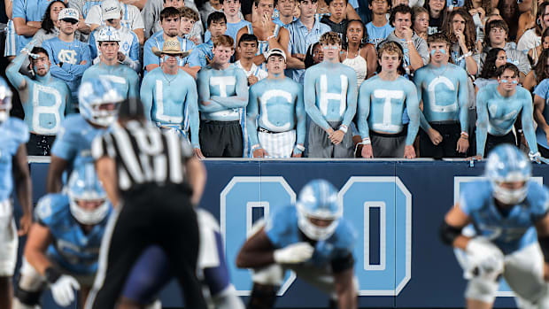 UNC fans with the name “BELICHICK” painted on their chests watch the game from the stands.