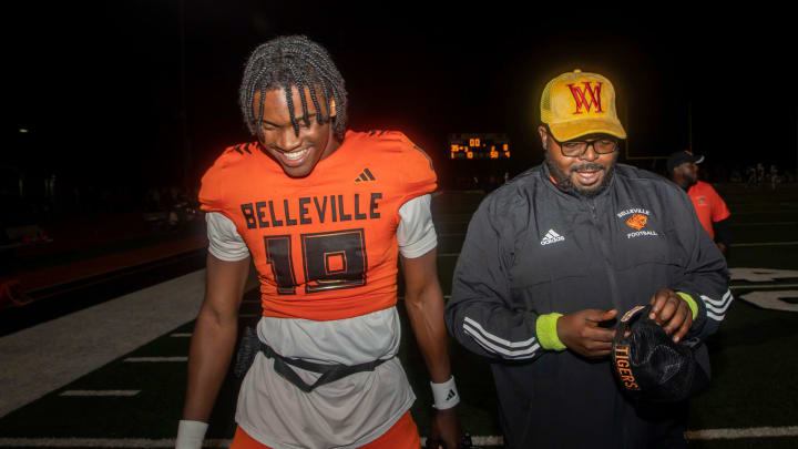 Belleville quarterback Bryce Underwood (19) walks next to one of his coaches, LeeAndrew Omorogieva, at the end of a 35-8 victory against Westland Glenn in Belleville on Friday, Sept. 29, 2023.