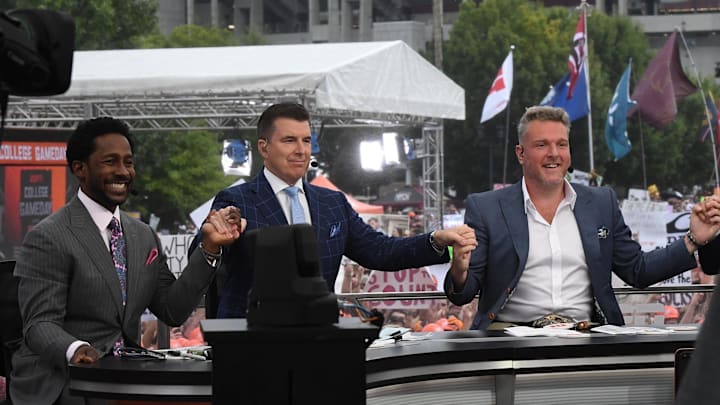 Desmond Howard, left, Rece Davis, and Pat McAfee hold hands for a photo before starting live broadcast during ESPN Gameday near Williams-Brice Stadium in Columbia, S.C. Saturday, September 14, 2024.