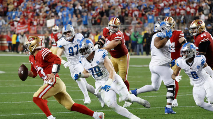 49ers quarterback Brock Purdy looks to run the ball around Lions defensive end John Cominsky.