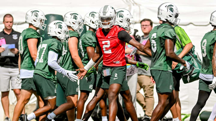 Michigan State quarterback Aidan Chiles, center, slaps hands with teammates during the first day of football camp on Tuesday, July 30, 2024, in East Lansing.