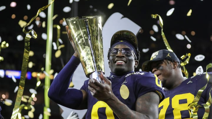 Michigan defensive back Mike Sainristil lifts the trophy to celebrate the 34-13 win over Washington at the national championship game at NRG Stadium in Houston on Monday, Jan. 8, 2024.