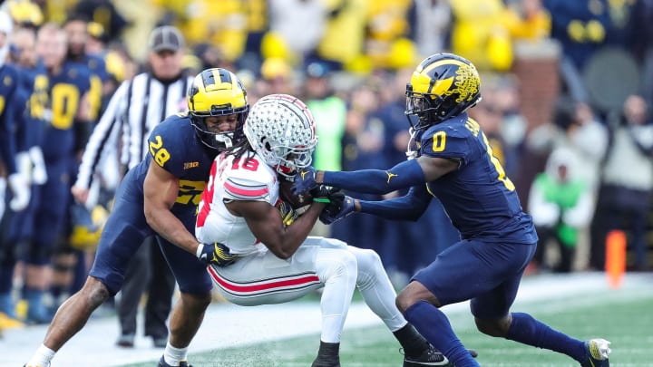 Ohio State wide receiver Marvin Harrison Jr. (18) makes a catch against Michigan defensive back Quinten Johnson (28) and defensive back Mike Sainristil (0) during the second half at Michigan Stadium in Ann Arbor on Saturday, Nov. 25, 2023.