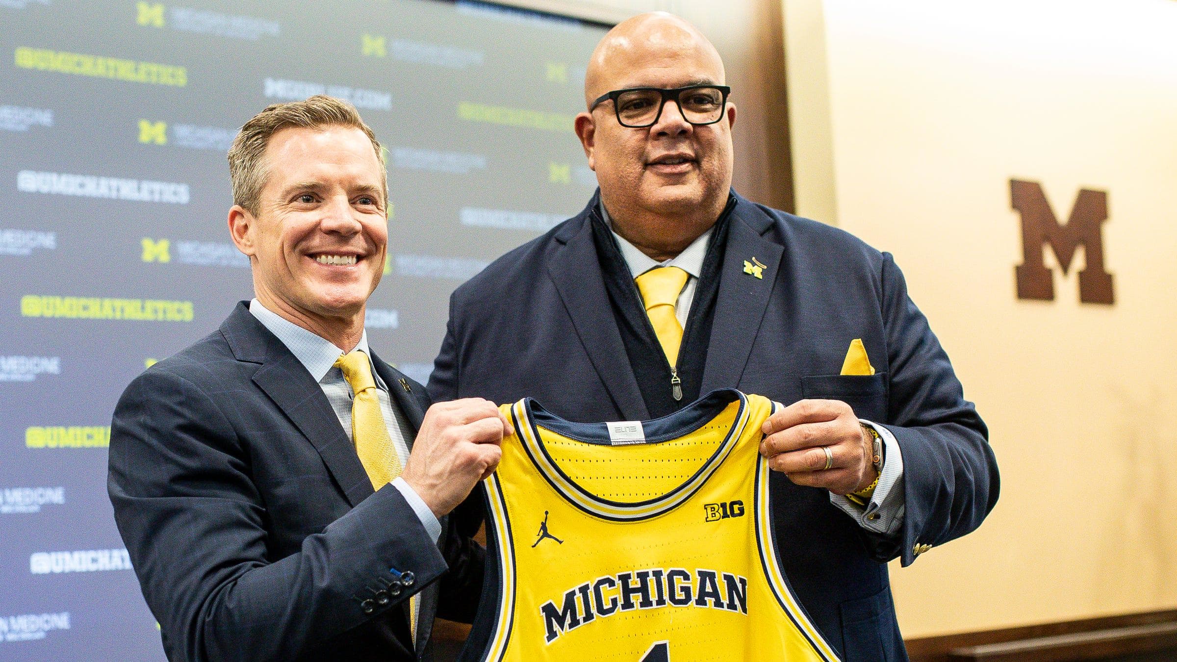 Michigan athletic director Warde Manuel presents a jersey to May during his introduction.