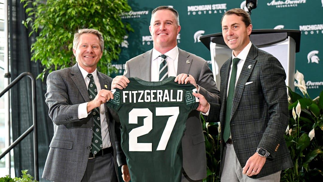 Michigan State football's new coach Pat Fitzgerald, center, holds up a jersey with MSU president Kevin Guskiewicz, left, and athletic director J Batt, right, during Fitzgerald's introductory press conference on Tuesday, Dec. 2, 2025, at the Tom Izzo Football Building in East Lansing. Michigan State football's new coach Pat Fitzgerald, center, holds up a jersey with MSU president Kevin Guskiewicz, left, and athletic director J Batt, right, during Fitzgerald's introductory press conference on Tuesday, Dec. 2, 2025, at the Tom Izzo Football Building in East Lansing.