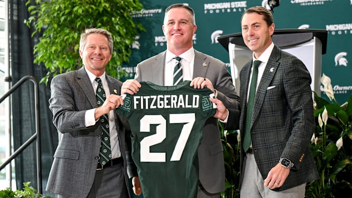 Michigan State football's new coach Pat Fitzgerald, center, holds up a jersey with MSU president Kevin Guskiewicz, left, and athletic director J Batt, right, during Fitzgerald's introductory press conference on Tuesday, Dec. 2, 2025, at the Tom Izzo Football Building in East Lansing.