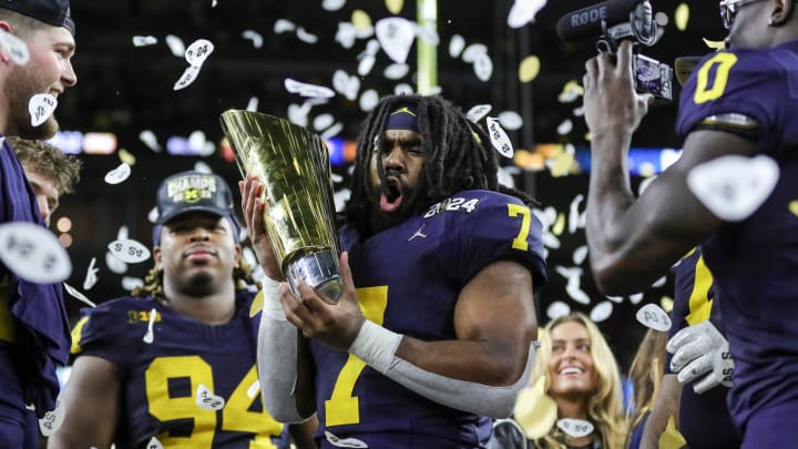 Michigan running back Donovan Edwards picks up the trophy to celebrate 34-13 win over Washington at the national championship game at NRG Stadium in Houston on Monday, Jan. 8, 2024.