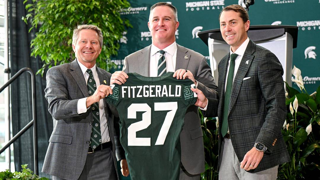 Michigan State football's new coach Pat Fitzgerald, center, holds up a jersey with MSU president Kevin Guskiewicz, left, and athletic director J Batt, right Michigan State football's new coach Pat Fitzgerald, center, holds up a jersey with MSU president Kevin Guskiewicz, left, and athletic director J Batt, right