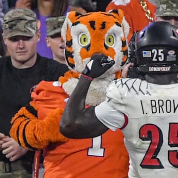 Nov 2, 2024; Clemson, South Carolina, USA; Louisville Cardinals running back Isaac Brown (25) flexes his muscles in front of the Clemson Tigers Tiger mascot after scoring in the fourth quarter at Memorial Stadium. Mandatory Credit: Ken Ruinard-Imagn Images