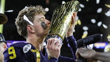 Michigan quarterback J.J. McCarthy kisses the championship trophy to celebrate the Wolverines' 34-13