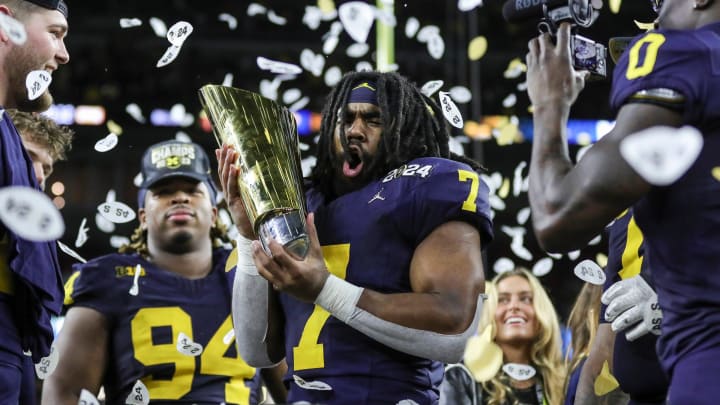 Michigan running back Donovan Edwards (7) picks up the trophy to celebrate the Wolverines' 34-13 win over Washington at the national championship game at NRG Stadium in Houston on Monday, Jan. 8, 2024.