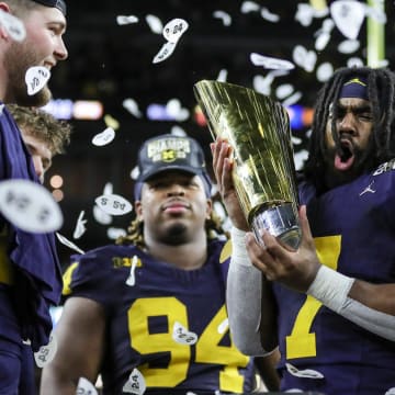 Michigan running back Donovan Edwards (7) picks up the trophy to celebrate the Wolverines' 34-13 win over Washington at the national championship game at NRG Stadium in Houston on Monday, Jan. 8, 2024.
