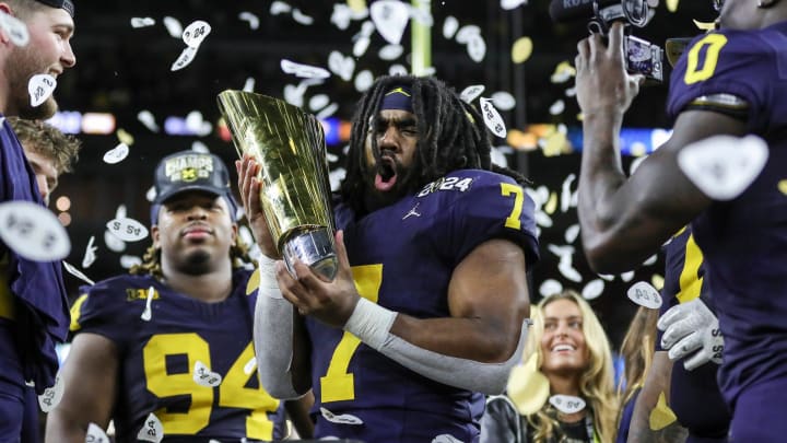 Michigan running back Donovan Edwards (7) picks up the trophy to celebrate the Wolverines' 34-13 win over Washington at the national championship game at NRG Stadium in Houston on Monday, Jan. 8, 2024.