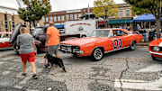 People walk by cars, including television show Dukes of Hazard famed car named General Lee during the Belton Standpipe Festival.