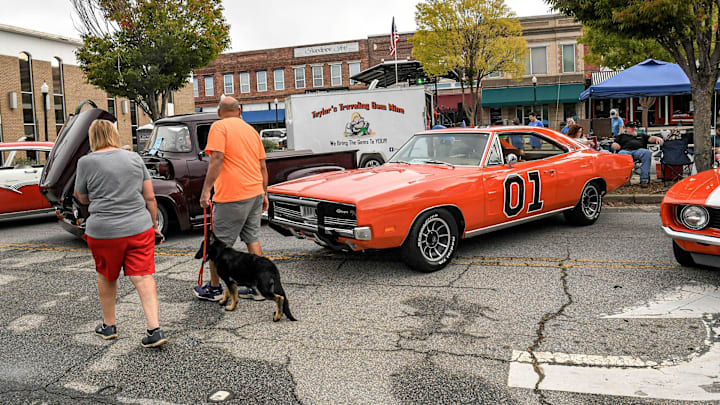 People walk by cars, including television show Dukes of Hazard famed car named General Lee during the Belton Standpipe Festival.