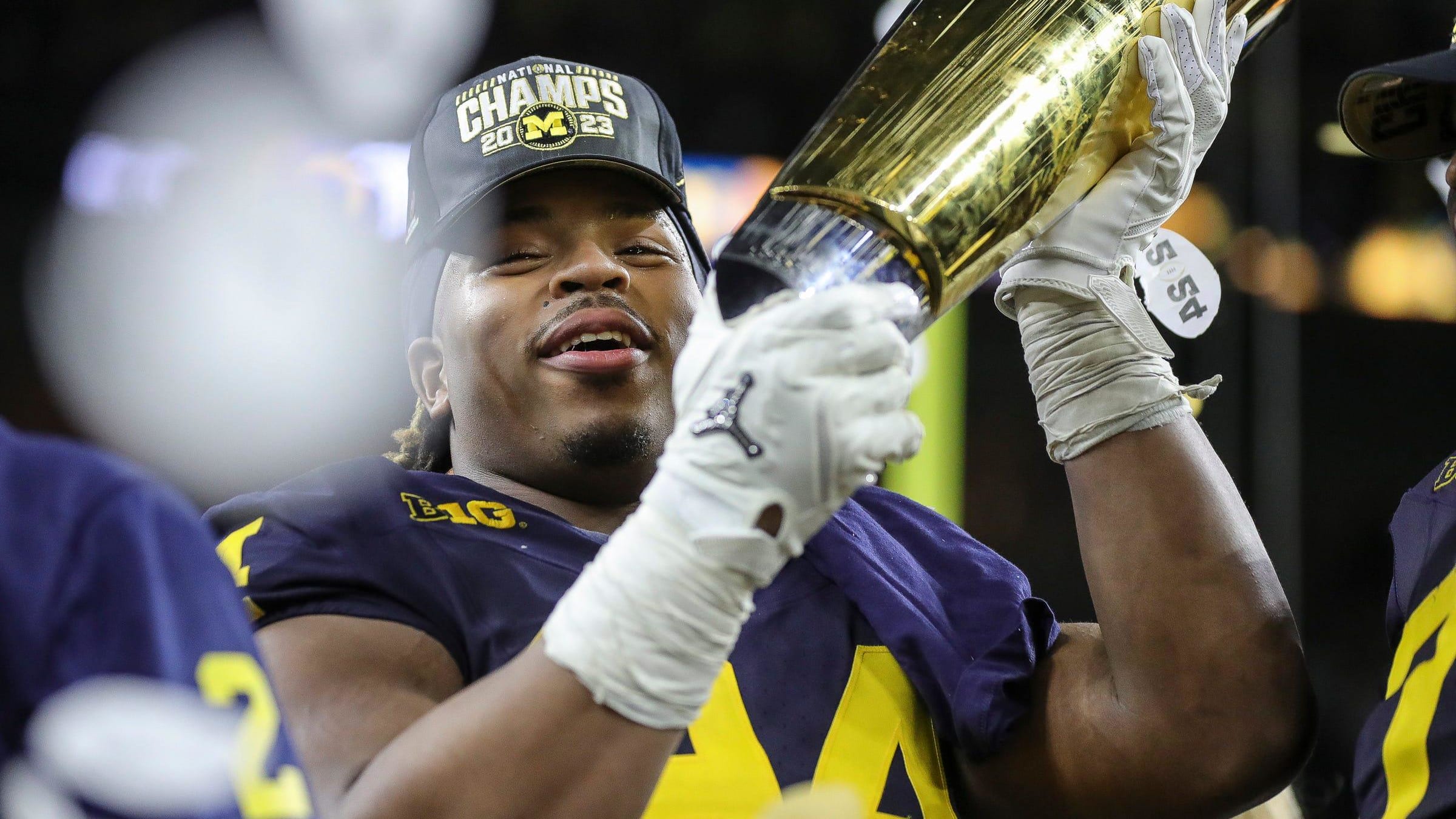 Michigan defensive lineman Kris Jenkins (94) picks up the trophy to celebrate the Wolverines' 34-13