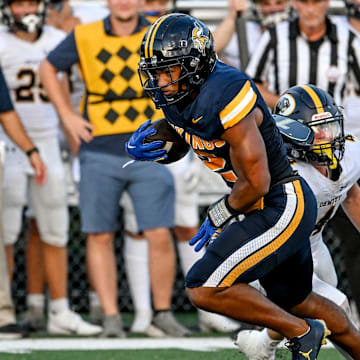 Haslett's Kory Amachree, left, breaks a tackle attempt by DeWitt's Abram Larner on his way to a touchdown during the first quarter in the game against DeWitt on Thursday, Aug. 29, 2024, at Haslett High School.