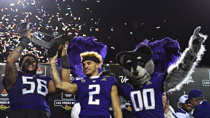 Former Husky center Nick Harris  (56) and wide receiver Aaron Fuller (2) hoist the Las Vegas Bowl trophy at Sam Boyd Stadium in 2019.