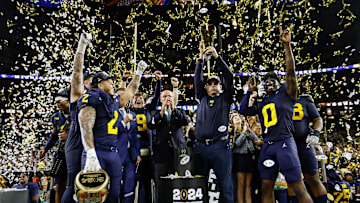Michigan head coach Jim Harbaugh lifts up the trophy as players and coaches celebrate after their