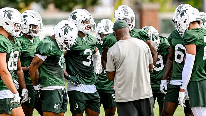 Michigan State's wide receivers gather around coach Courtney Hawkins during the first day of football camp on Tuesday, July 30, 2024, in East Lansing.