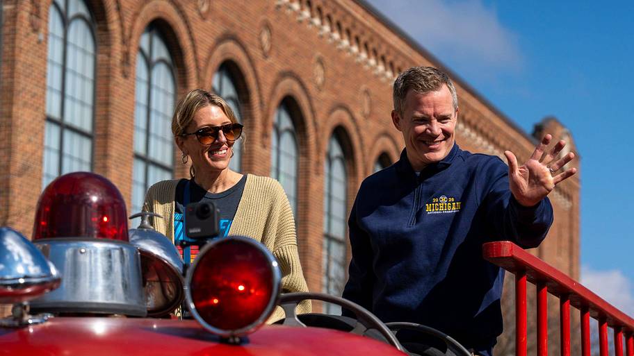 Anna May (left) and Dusty May (right) ride in a fire truck to celebrate Michigan’s national championship.