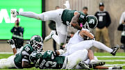 From left, Michigan State's Armorion Smith, Malik Spencer and Jordan Hall tackle Penn State's Trebor Pe–a during the first quarter on Saturday, Nov. 15, 2025, at Spartan Stadium in East Lansing.