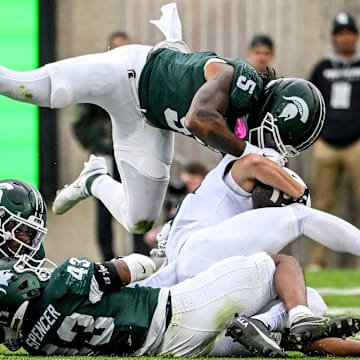 From left, Michigan State's Armorion Smith, Malik Spencer and Jordan Hall tackle Penn State's Trebor Pe–a during the first quarter on Saturday, Nov. 15, 2025, at Spartan Stadium in East Lansing.