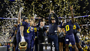 Michigan head coach Jim Harbaugh lifts up the trophy as players and coaches celebrate after their