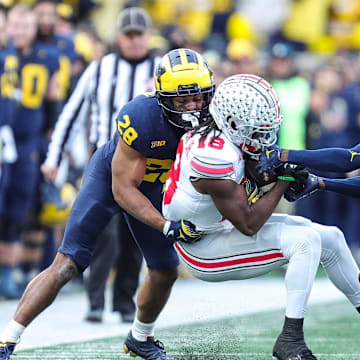 Ohio State wide receiver Marvin Harrison Jr. (18) makes a catch against Michigan defensive back Quinten Johnson (28) and defensive back Mike Sainristil (0) during the second half at Michigan Stadium in Ann Arbor on Saturday, Nov. 25, 2023.