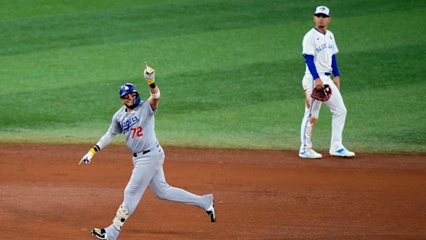 Dodgers second baseman Miguel Rojas rounds the bases after hitting a home run as Blue Jays shortstop Andres Gimenez looks on.